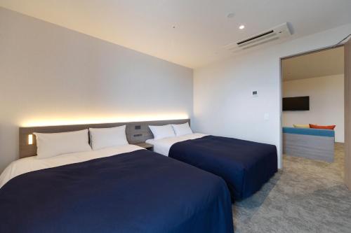 a hotel room with two beds and a television at Minn STATION Ai Nagoya in Aoichō