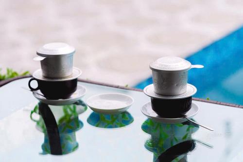 three bottles with cups on top of a glass table at Mountain Flower Bungalow & Homestay in Ninh Binh