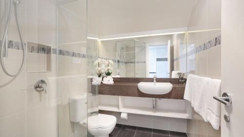 a white bathroom with a sink and a toilet at Centennial Views Apartment in Bowral