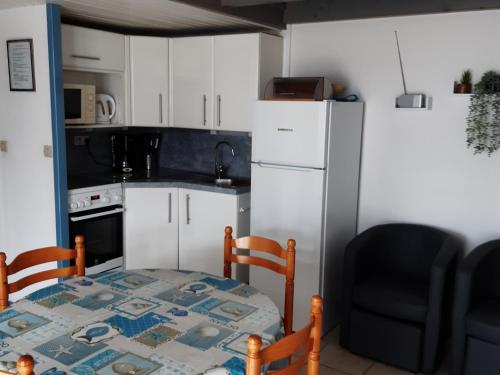 une petite cuisine avec une table et un réfrigérateur dans l'établissement Maisonnette cosy à Barbâtre, bordure forêt, proche plage - FR-1-823-6, à Barbâtre