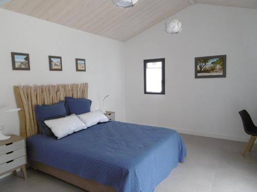 - une chambre avec un lit bleu et une chaise dans l'établissement Noirmoutier - Villa 8 Pers - Grand Jardin - Standing - FR-1-823-10, à Noirmoutier-en-l'lle