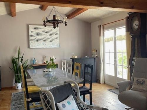 une salle à manger avec une table, des chaises et une horloge dans l'établissement Maison Confortable Noirmoutier pour 6 Pers, Jardin Clôturé - FR-1-823-11, à Barbâtre