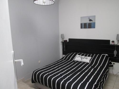 - une chambre avec un lit rayé noir et blanc dans l'établissement Maison à Barbâtre, proche plage, animaux admis - FR-1-823-37, à Barbâtre