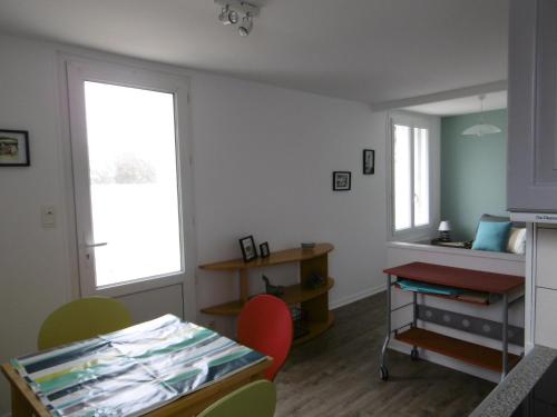 Cette chambre comprend un bureau et une table avec des chaises. dans l'établissement Maison cosy à Barbâtre, proche plage, jardin, 2 pers. - FR-1-823-39, à Barbâtre