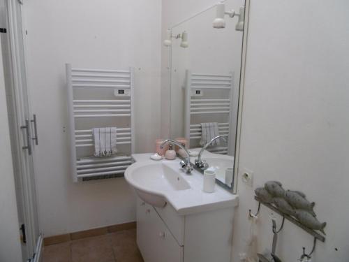 un bagno bianco con lavandino e specchio di Maison confortable 4 pers. avec jardin fermé à L'Épine, proche plage - FR-1-823-27 a LʼÉpine