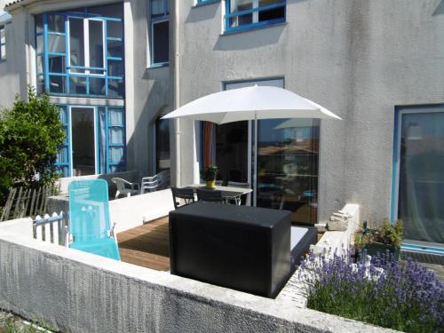 une terrasse avec une table, un parasol et une télévision dans l'établissement Rez-de-jardin 4 pers proche plage et port Noirmoutier - FR-1-823-32, à Noirmoutier-en-l'lle