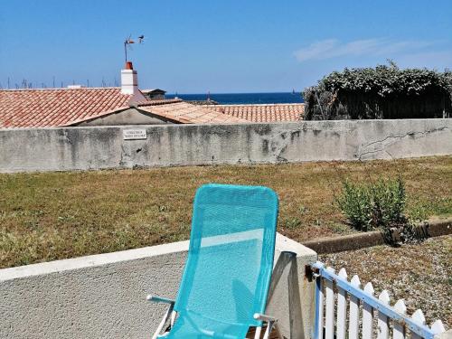 une chaise bleue assise sur une corniche à côté d'une clôture dans l'établissement Rez-de-jardin 4 pers proche plage et port Noirmoutier - FR-1-823-32, à Noirmoutier-en-l'lle