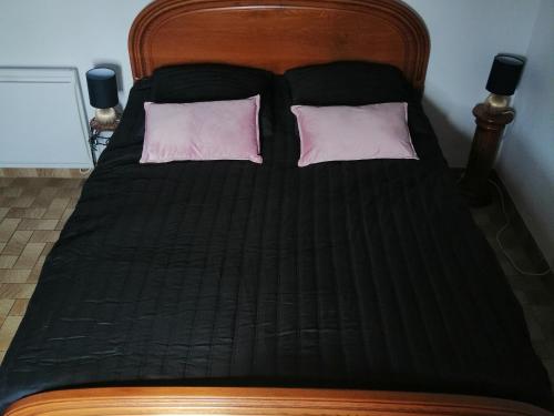 a black bed with two pink pillows on it at Maison à Noirmoutier proche plage, animaux admis - FR-1-823-34 in Noirmoutier-en-l'lle