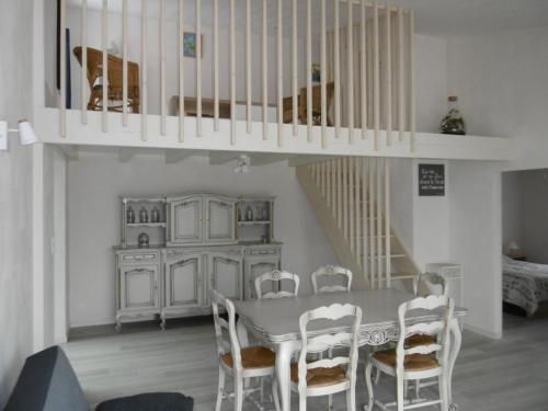 une salle à manger avec une table et des chaises et un escalier dans l'établissement Maison rénovée 6 pers, proche de la plage, terrasse et parking - FR-1-823-47, à LʼÉpine