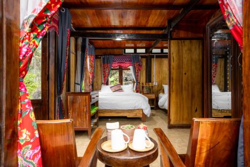 a bedroom with a bed and a table and chairs at Mế farmstay in Cao Bằng