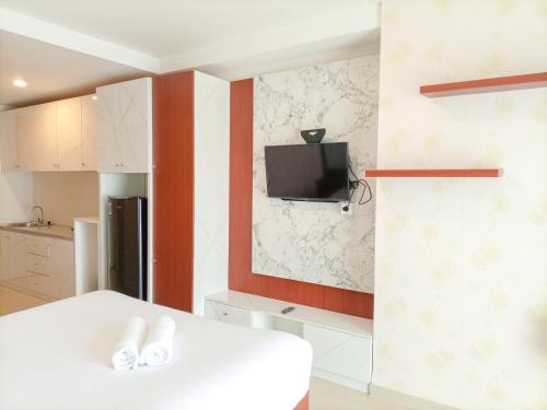 cocina blanca con TV en la pared en Elegant and MInimalist Studio at Mataram City Apartment By Travelio, en Kejayan