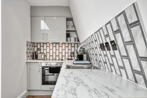 a white kitchen with a marble counter top at Bright & Glamorous Apartment 1BR 1BA Private Balcony in London