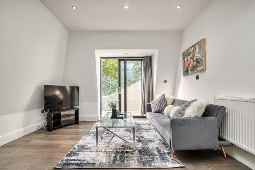 a living room with a couch and a tv at Bright & Glamorous Apartment 1BR 1BA Private Balcony in London