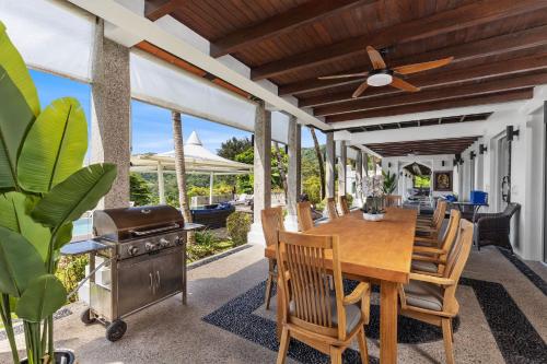an outdoor dining room with a table and a grill at Spectacular Ocean Views 8BR Pool Villa Sawan in Patong! Relax & Play - Billiard, Table football, Gym & Sauna! in Patong Beach