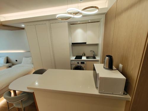 a small room with a bed and a white table with a microwave at W Residence Hotel Centum City in Busan