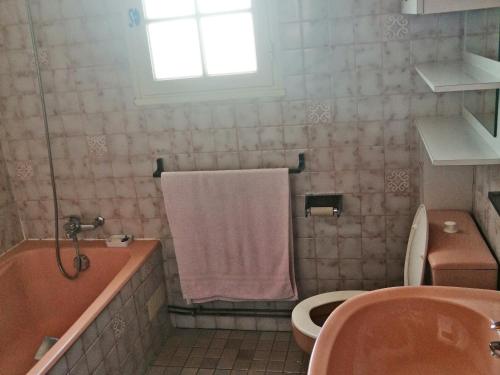 La salle de bains est pourvue d'une baignoire rose, de toilettes et d'un lavabo. dans l'établissement Maison à Noirmoutier - Proche plage & forêt - Animaux admis - FR-1-823-65, à Noirmoutier-en-l'lle