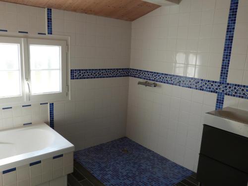 La salle de bains est pourvue d'un lavabo et de carrelage bleu et blanc. dans l'établissement Maison Confortable Barbâtre 4/6 Pers - Proche Plage et Commerces - WiFi Gratuit - FR-1-823-91, à Barbâtre