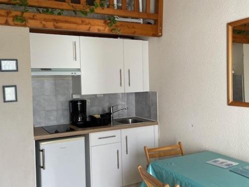 - une cuisine avec des placards blancs, un évier et une table dans l'établissement Maisonnette à 30m de la plage pour 4 pers - Barbâtre - FR-1-823-96, à Barbâtre