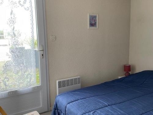une chambre avec un lit bleu et une fenêtre dans l'établissement Maisonnette à 30m de la plage pour 4 pers - Barbâtre - FR-1-823-96, à Barbâtre