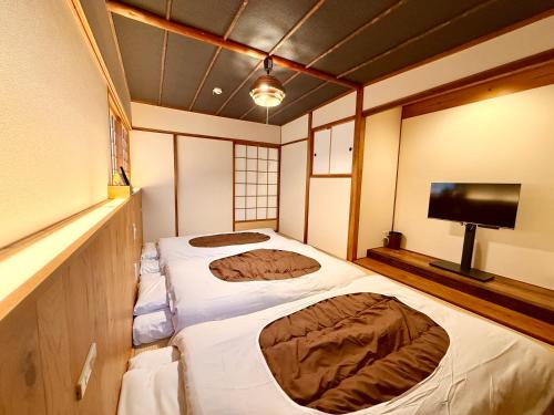 two beds in a small room with a tv at Miyazakiya Kitayama - Hanare - in Kyoto