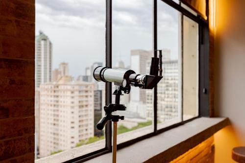 a camera on a tripod in front of a window at Edifício ASA | Conforto e Conveniência no Coração de Curitiba | Gonzaga Stays in Curitiba