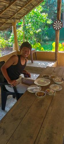 a man sitting at a table with plates of food at Sharta Unawatuna Hostel in Unawatuna