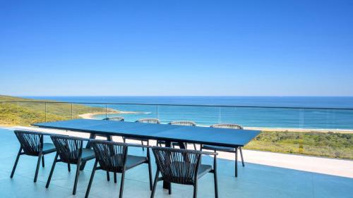 a blue table and chairs on a balcony with the ocean at 'Sea Mist' by HolidayCo in Hardys Bay