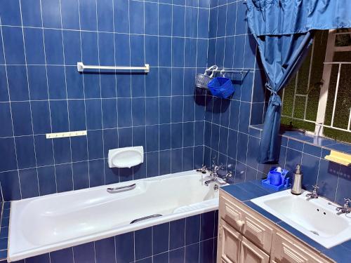 a blue tiled bathroom with a tub and a sink at El Roi apartment in Middelburg