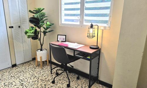 a desk with a computer and a potted plant at Jayuya Cozy Aparment with Wi-Fi, Free Parking and AC in Jayuya