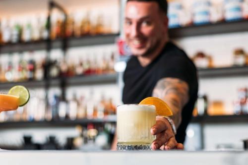 a man standing at a bar with a drink at Hotel TOTTO Wollongong in Wollongong