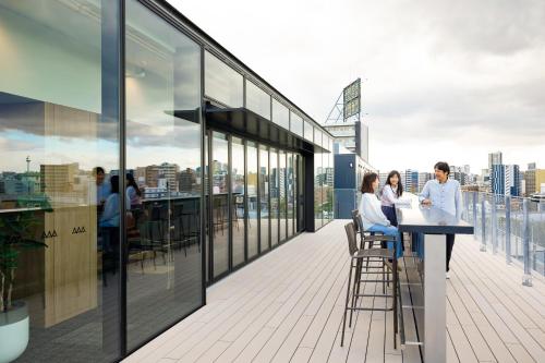 a group of people sitting at a table on a building balcony at Minn STATION Ai Nagoya in Aoichō