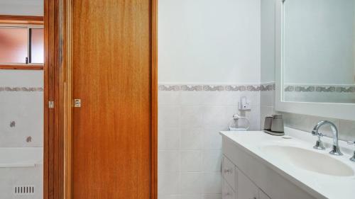 a bathroom with a sink and a wooden door at Umina Beach Coastal Getaway in Umina Beach 