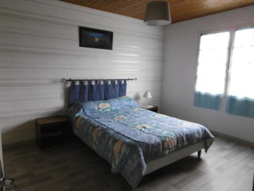 - une chambre avec un lit avec une couette bleue et 2 fenêtres dans l'établissement Maison spacieuse à Barbâtre, proche plage, animaux admis - FR-1-823-108, à Barbâtre