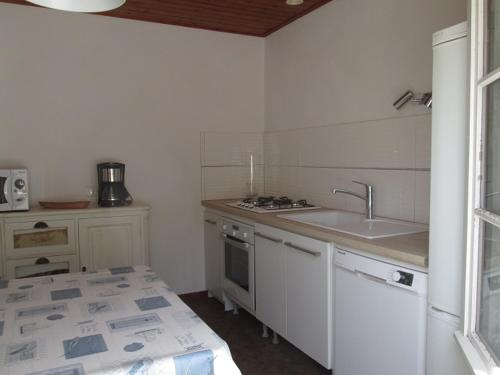 une cuisine blanche avec un évier et une cuisinière dans l'établissement Maison confortable à Barbâtre, proche plage, animaux admis - FR-1-823-110, à Barbâtre