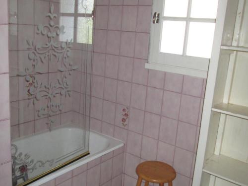 - une salle de bains carrelée de rose avec une baignoire et un tabouret dans l'établissement Maison confortable à Barbâtre, proche plage, animaux admis - FR-1-823-110, à Barbâtre
