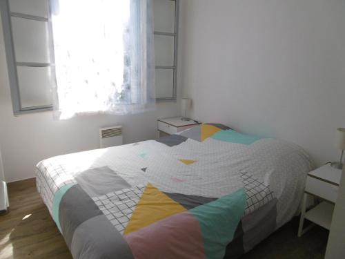 a bedroom with a bed with a colorful comforter at Charmante maisonnette proche plage - Animaux admis - FR-1-823-117 in Barbâtre