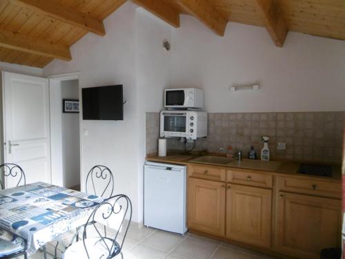 Il comprend une cuisine équipée d'un réfrigérateur blanc et d'une table avec des chaises. dans l'établissement Maison 2 Pers. à Noirmoutier, Proche Plage, Parking - FR-1-823-115, à Noirmoutier-en-l'lle