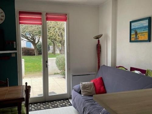 a living room with a couch and a sliding glass door at Maisonnette à Barbâtre, proche plage, animaux admis, 2-4 pers. - FR-1-823-118 in Barbâtre