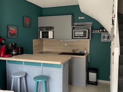 une cuisine avec des murs verts et un comptoir avec des tabourets dans l'établissement Maisonnette à Barbâtre, proche plage, animaux admis, 2-4 pers. - FR-1-823-118, à Barbâtre