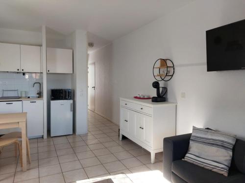 un salon avec un canapé et une cuisine dans l'établissement Charmant T2 avec piscine à 2 min de la plage - FR-1-239-1104, à Urrugne