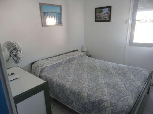 une chambre avec un lit, une table et une fenêtre dans l'établissement Appt climatisé, 4 pers, piscine et parking - Le Grau-du-Roi - FR-1-250-300, au Grau-du-Roi