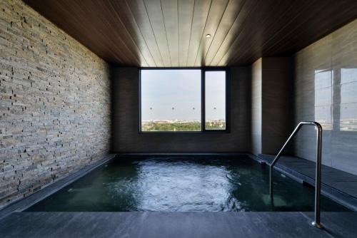 a hot tub in a room with a window at Hotel Nikko Amata City Chonburi in Chon Buri