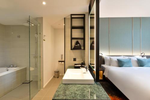 a bathroom with a bed and a sink and a bath tub at Hotel Nikko Amata City Chonburi in Chon Buri