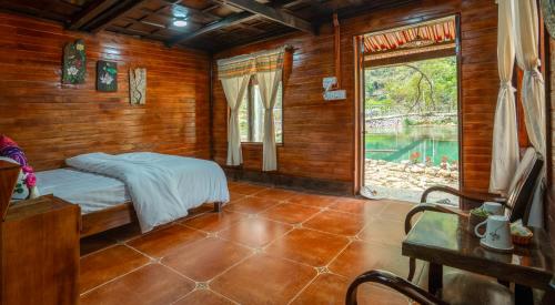 a bedroom with a bed in a wooden room with a window at Mế farmstay in Cao Bằng
