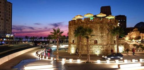 an old stone building with palm trees in a city at Backpackers Casa De Payaso in Durrës