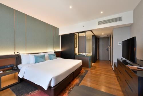 a bedroom with a bed and a flat screen tv at Hotel Nikko Amata City Chonburi in Chon Buri