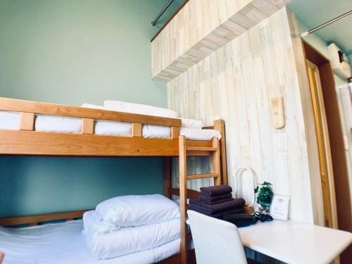 a room with two bunk beds and a table and a desk at イーストコート長崎 in Tokyo