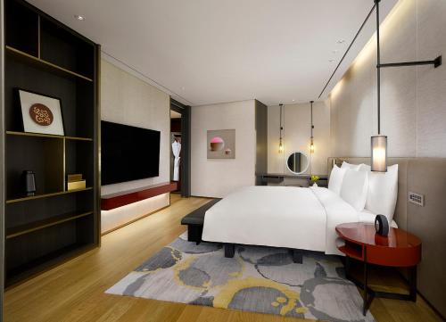 a bedroom with a large white bed and a tv at Grand Hyatt Jeju in Jeju