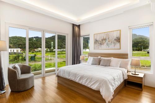 une chambre avec un lit, une chaise et des fenêtres dans l'établissement The House at Bluestone, à Los Baños