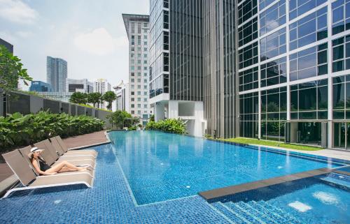 新加坡Ascott Orchard Singapore的一位女士坐在游泳池边的椅子上